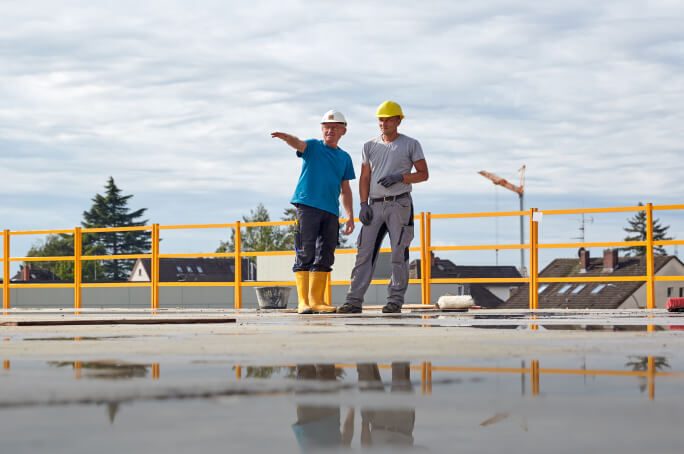 Zwei Mitarbeiter stehen auf Bodenplatte Leistungen Hochbau
